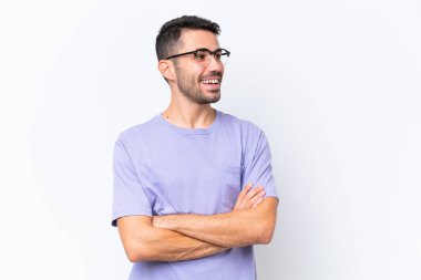 Beyaz arka planda izole edilmiş genç beyaz adam mutlu ve gülümsüyor.