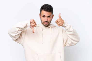 Beyaz arka planda izole edilmiş beyaz bir adam iyiye-kötüye işaret yapıyor. Evet ya da hayır arasında kararsız