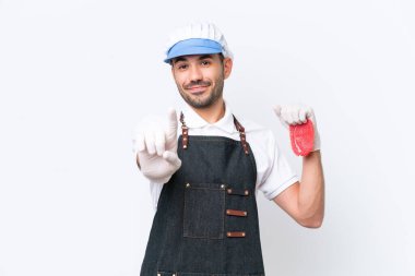 Kasap beyaz önlük giymiş ve izole edilmiş beyaz arka planda taze et servis ediyor ve parmağını kaldırıyor.
