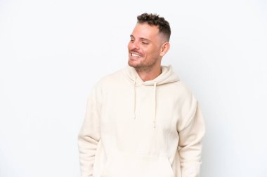 Beyaz arka planda soyutlanmış beyaz tenli yakışıklı bir adam yan tarafa bakıyor ve gülümsüyor.