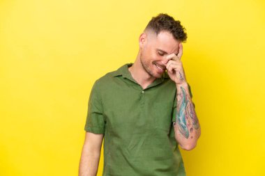 Sarı arka planda izole edilmiş genç beyaz yakışıklı adam gülüyor.