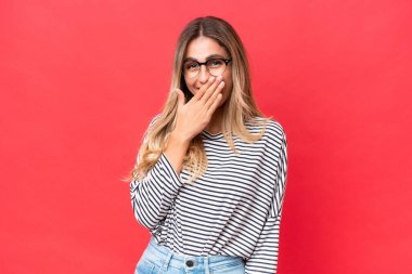 Genç Uruguaylı kadın kırmızı arka planda izole edilmiş mutlu ve ağzı kapalı gülümsüyor.