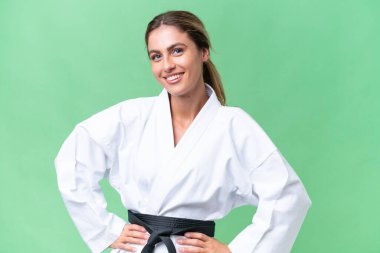 Genç Uruguaylı kadın izole edilmiş arka planda karate yapıyor. Kolları kalçasında ve gülümsüyor.