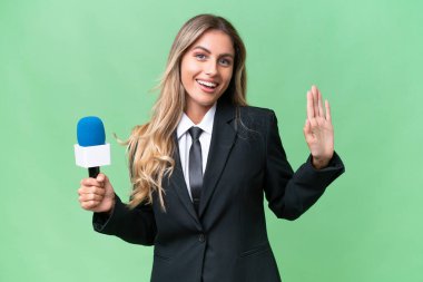 Genç, güzel Uruguaylı televizyon sunucusu izole edilmiş arka planda mutlu bir ifadeyle selamlama yapıyor.