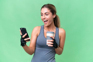 Güzel Sport Uruguaylı kadın izole edilmiş arka planda kahve ve bir cep telefonu tutuyor.