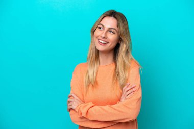 Genç Uruguaylı kadın mavi arka planda izole edilmiş mutlu ve gülümsüyor.