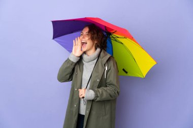 Mor arka planda izole edilmiş bir şemsiye tutan İngiliz kadın ağzı sonuna kadar açık bağırıyor.