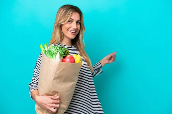 Young Uruguayan Woman Holding Grocery Shopping Bag Isolated Blue Background — Stock Photo, Image