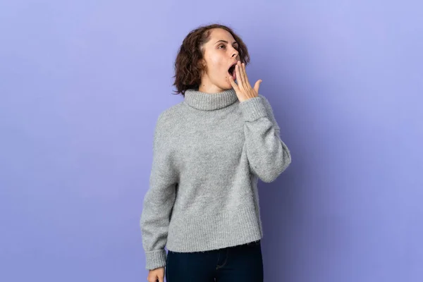 Young English woman isolated on purple background yawning and covering wide open mouth with hand