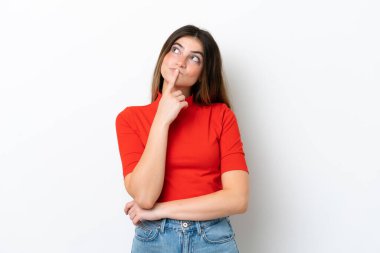 Beyaz arka planda izole edilmiş genç beyaz kadın yukarı bakarken şüpheleri var.