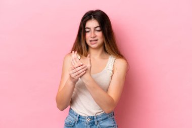 Pembe arka planda izole edilmiş beyaz bir kadın ellerinde acıdan muzdarip.