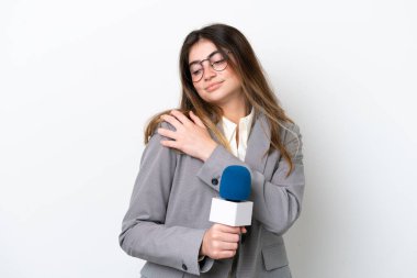 Beyaz arka planda izole edilmiş beyaz bir televizyon sunucusu olan genç beyaz kadın omuz ağrısından muzdarip.