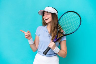 Young tennis player woman isolated on blue background pointing finger to the side and presenting a product