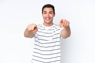 Beyaz arka planda izole edilmiş genç beyaz adam şaşırmış ve ön tarafı işaret ediyor.