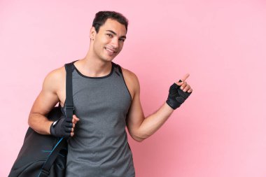 Pembe arka planda izole edilmiş spor çantalı, beyaz, genç bir adam.