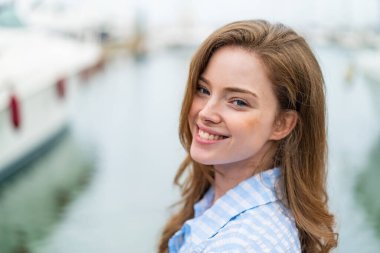 Açık havada kızıl saçlı genç bir kadın Neşeli bir ifadeyle