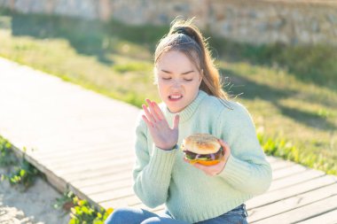 Genç ve güzel bir kız elinde hamburgerle dışarıda