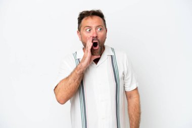 Beyaz arka planda izole edilmiş orta yaşlı beyaz bir adam yan tarafa bakarken sürpriz bir jest yaparak bir şeyler fısıldıyor.