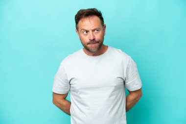 Orta yaşlı, beyaz bir adam mavi arka planda izole edilmiş.