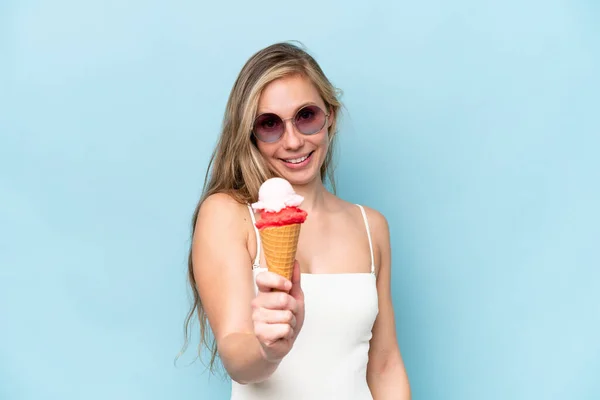 幸せな表情で青い背景に隔離されたアイスクリームを保持する水着の若い金髪の女性 — ストック写真