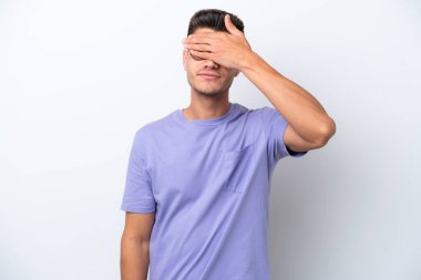 Beyaz arka planda izole edilmiş beyaz tenli genç bir adam gözlerini elleriyle kapatıyor. Bir şey görmek istemiyorum.