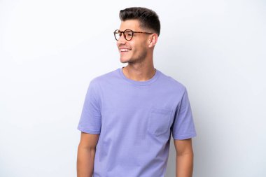 Beyaz arka planda izole edilmiş genç beyaz adam yana bakıyor ve gülümsüyor.