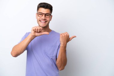 Beyaz arka planda izole edilmiş genç beyaz bir adam bir ürün sunmak için kenarı işaret ediyor.