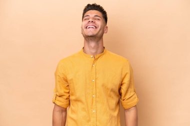 Beyazlı genç bir adam bej arka planda izole edilmiş gülüyor.