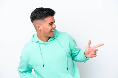 Beyaz arka planda izole edilmiş beyaz tenli yakışıklı bir adam, parmağını yana uzattı ve bir ürün sundu.
