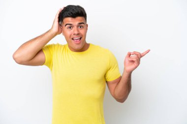 Beyaz arka planda izole edilmiş beyaz tenli yakışıklı bir adam şaşırmış ve parmağıyla kenarı işaret ediyor.