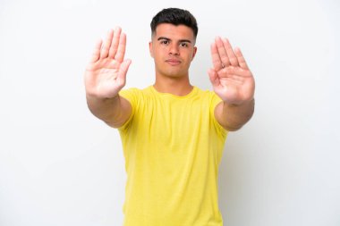 Beyaz arka planda izole edilmiş beyaz tenli yakışıklı genç adam dur hareketi yapıyor ve hayal kırıklığına uğruyor.