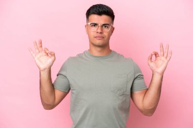 Zen pozisyonunda pembe arka planda izole edilmiş beyaz yakışıklı bir adam.