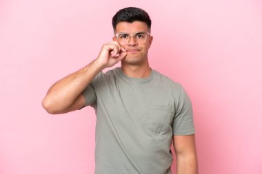 Pembe arka planda izole edilmiş beyaz yakışıklı genç bir adam sessizlik işareti gösteriyor.
