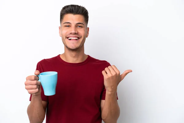 stock image Young caucasian man holding cup of coffee isolated on white background pointing to the side to present a product