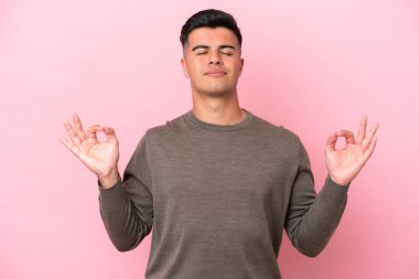 Zen pozisyonunda pembe arka planda izole edilmiş beyaz yakışıklı bir adam.