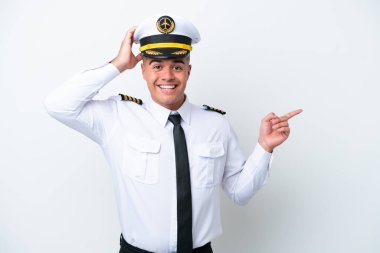 Uçak pilotu beyaz arka planda izole edilmiş beyaz bir beyaz adam şaşırmış ve parmağını kenarı işaret ediyor.