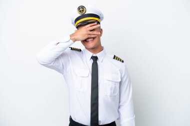 Uçak pilotu beyaz arka planda izole edilmiş beyaz bir beyaz adam gözlerini elleriyle kapatıyor ve gülümsüyor.