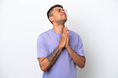 Beyaz arka planda izole edilmiş beyaz Brezilyalı genç adam avuç içlerini bir arada tutuyor. İnsan bir şey ister.