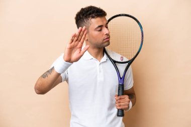 Bej arka planda tenis oynayan genç Brezilyalı yakışıklı adam dur hareketi yapıyor ve hayal kırıklığına uğruyor.