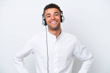 Tele pazarlamacı Brezilyalı adam beyaz arka planda izole edilmiş bir kulaklıkla çalışıyor. Kolları kalçasında ve gülümsüyor.