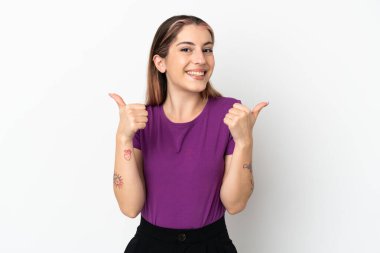 Beyaz arka planda izole edilmiş beyaz bir kadın. Baş parmakları havada ve gülümsüyor.