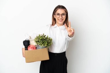 Young caucasian woman moving in new home among boxes isolated on white background smiling and showing victory sign