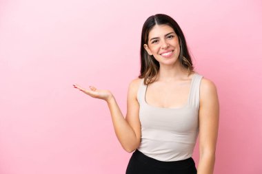 Pembe arka planda izole edilmiş genç bir İtalyan kadın gülümseyerek bir fikir sunuyor.