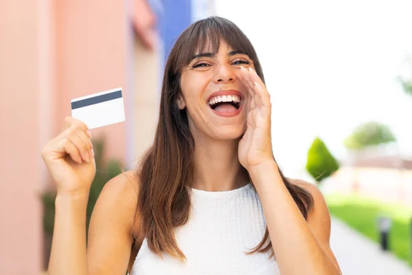 アウトドアでクレジットカードを持っている若い女性は 口を大きく開いて叫びます — ストック写真