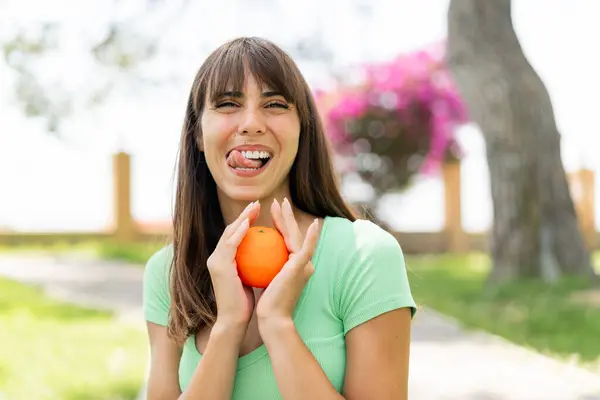 Mladá Žena Venku Drží Pomeranč Šťastným Výrazem — Stock fotografie