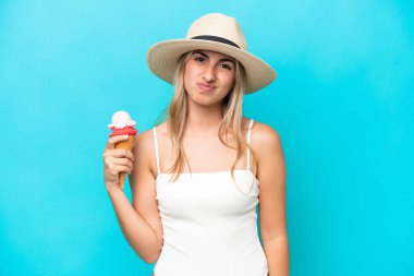 Mavi arka planda mahsur kalmış kornet dondurmalı mayolu beyaz bir kadın hüzünlü bir ifadeyle