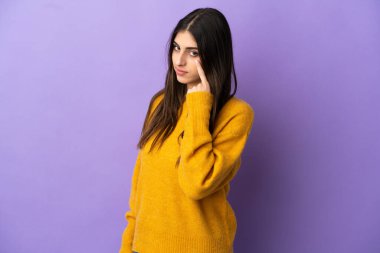 Mor arka planda izole edilmiş genç beyaz kadın bir şey gösteriyor.