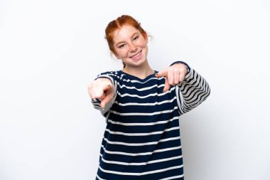 Young reddish woman isolated on white background pointing front with happy expression
