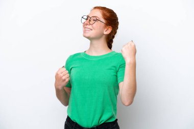 Young reddish woman isolated on white background celebrating a victory