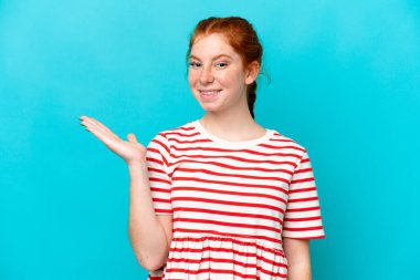 Kırmızımsı genç bir kadın mavi arka planda izole edilmiş bir şekilde bir fikir sunuyor.